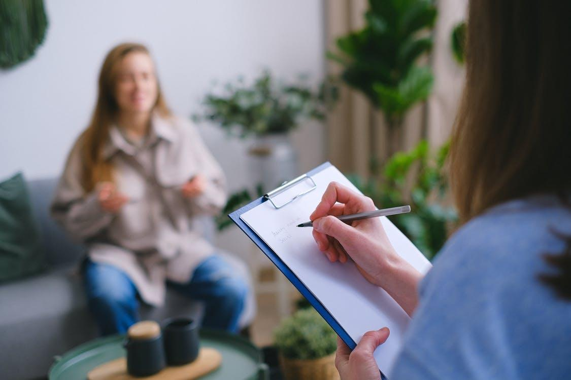 A woman at a clinic while a health expert takes notes