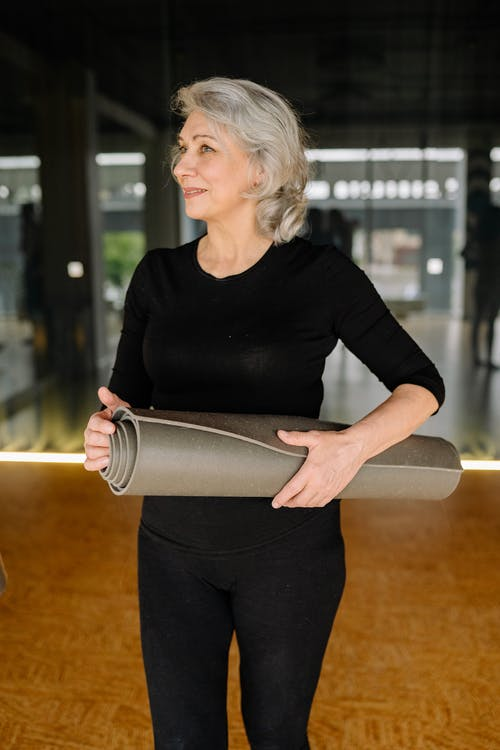 A woman holding a yoga mat 